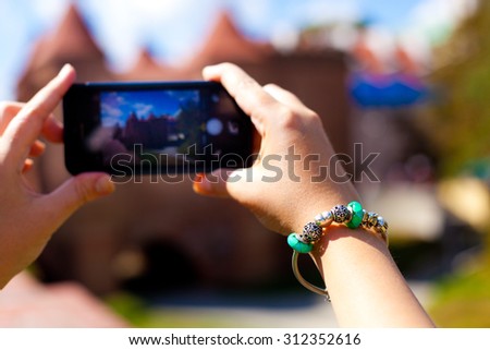 Tourist taking pictures on her phone. Hands with beautiful bracelet holding phone