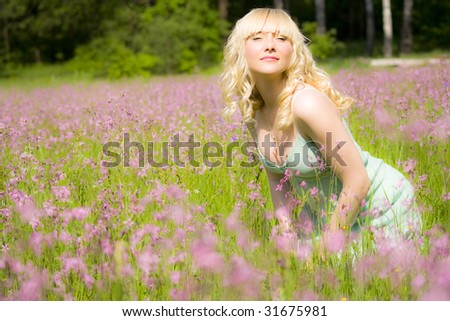 This is young, beautiful woman. She\'s enjoying scent of flowers.She is blond in gentle green dress. She is happy