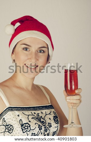 Young smiling woman  in a New Year\'s cap hoding with glass of red wine