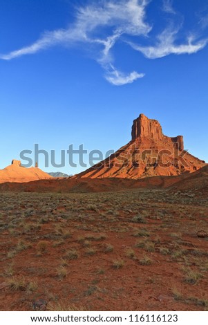 Parriott Mesa rises from the desert under a bird-like cloud formation near Moab, Utah