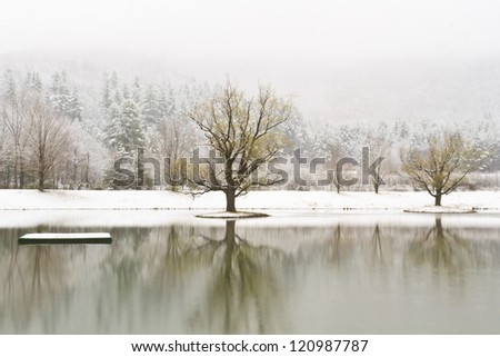 A platform and islands on a calm Catskills lake with snow-covered mountains behind near Big Indian, New York