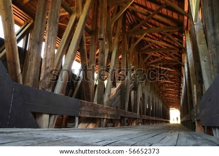 Two people walk into the unearthly light at the end of the historic Blenheim covered bridge, the longest wooden covered bridge in New York State.