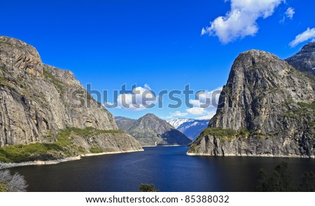 Kolana Rock and Hetch Hetchy Dome straddle the reservoir, with snow-capped Racheria Mountain behind at  Hetch Hetchy Reservoir in Yosemite National Park, California