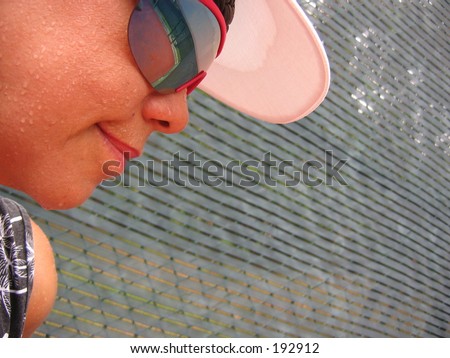 Lady’s face with perspiration against a tennis court net