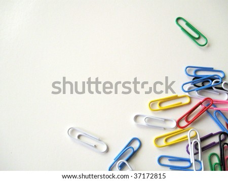 Colorful paper clips scattered on bottom right corner and isolated on white background.