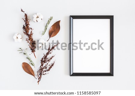 Autumn composition. Photo frame, dried flowers and leaves on white background. Autumn, fall concept. Flat lay, top view, copy space