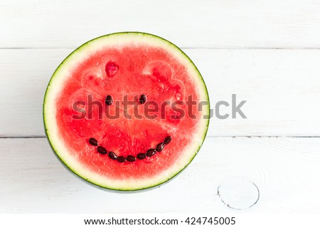 Watermelon with smile face. Funny watermelon on wooden white background. Top view, flat lay