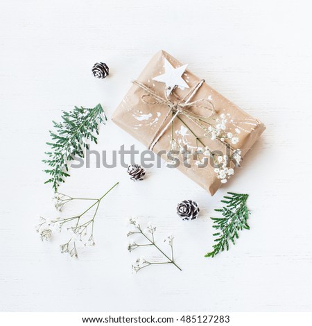 Christmas composition. Christmas gift, pine cones, thuja branches and gypsophila flowers. Top view, flat lay, square