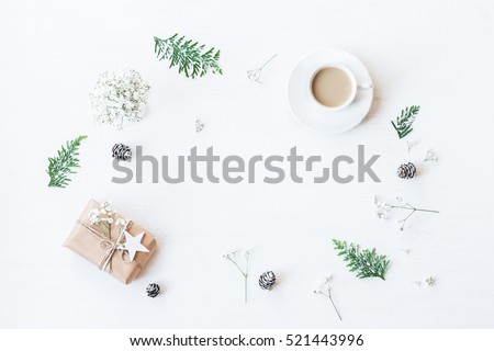 Christmas composition. Cup of coffee, christmas gift, pine cones, thuja branches and gypsophila flowers. Top view, flat lay