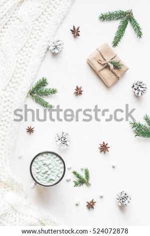 Christmas composition. Hot chocolate, christmas gift, knitted blanket, pine cones, fir branches. Flat lay, top view.