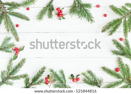 Christmas frame made of fir branches, red berries. Christmas wallpaper. Flat lay, top view.