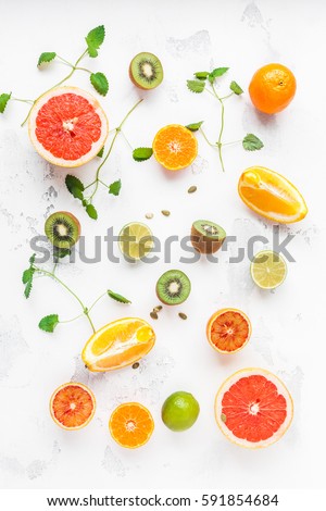 Colorful fresh fruit on white table. Orange, tangerine, lime, kiwi, grapefruit. Fruit pattern. Summer food concept. Flat lay, top view.
