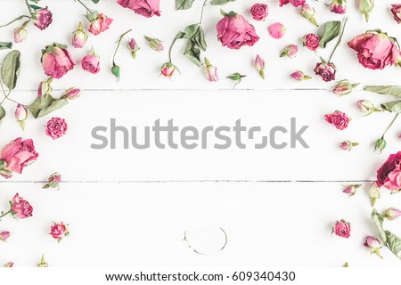 Flowers composition. Frame made of dried rose flowers on white wooden background. Flat lay, top view