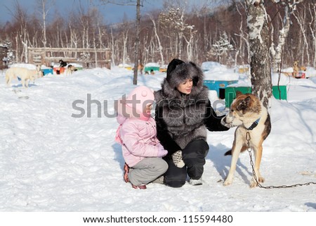 Mom and daughter stroking the dog in the kennel, Siberia, Russia
