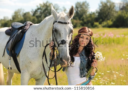 Beautiful girl walks on white horse on a summer meadow