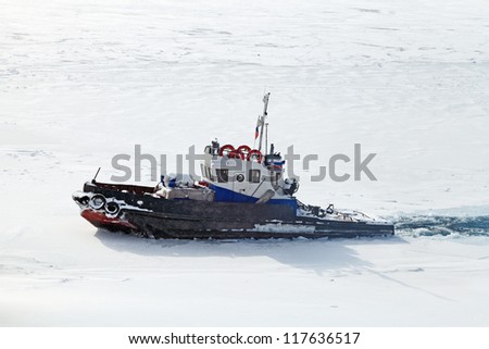 The little old ship floating in the winter the lake breaking the thin ice