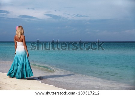 Young girl stands on the shore of the sea and looks into the distance