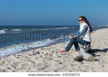 Thoughtful girl sits on the shore of the cold Baltic sea to the Curonian spit and looking afar