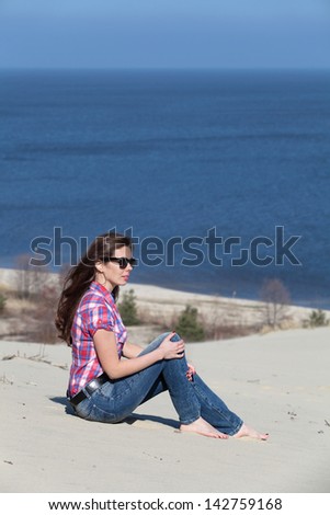 Young girl on the sand on the Curonian spit and looking afar