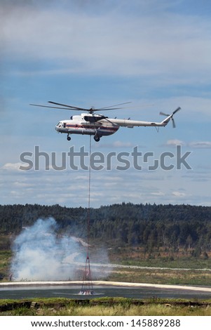 Fire helicopter draws up water from a fire reservoir for forest fire fighting