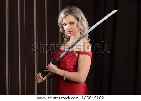 A young girl in a red dress and a samurai sword in hand on a dark background