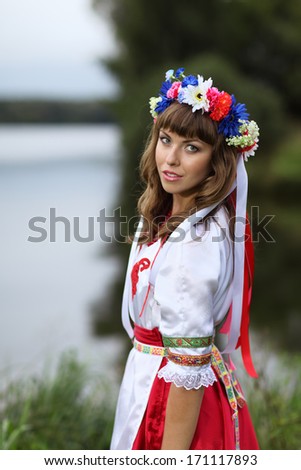 Portrait of a girl in the Ukrainian national costumes on the banks of the river