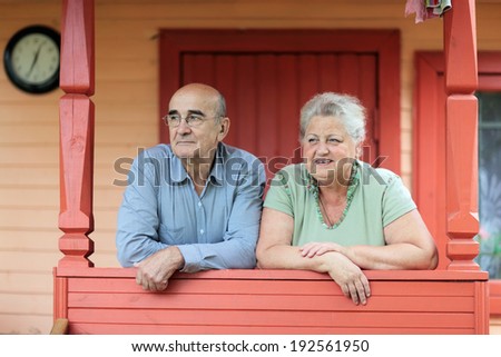 Happy couple pensioners on the porch of a country house