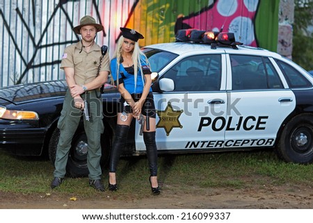 Armed police, a man and woman standing beside his car