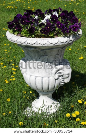 Vase with the flowers as an element of landscape design against a green lawn