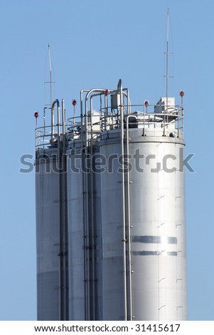 Tall metal silos for storing grain against a blue sky.