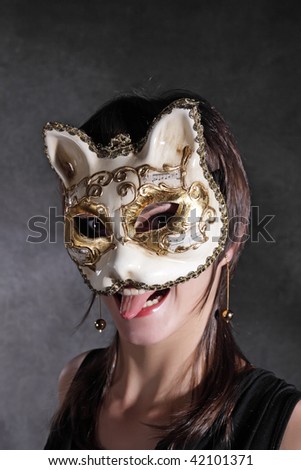 The young girl in the Venetian mask of a cat against a dark background