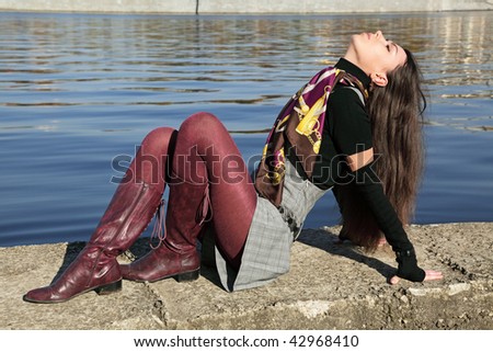 The beautiful girl sits on river bank Moscow, has cast away a head back