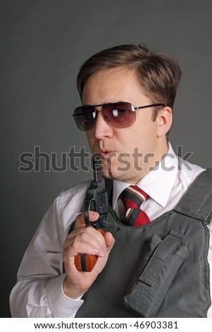 The man in a bullet-proof vest with a revolver on a grey background