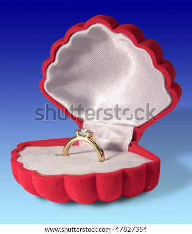 Gold ring with a jewel in a red gift box on a blue background