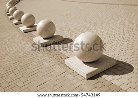 Protection in the form of decorative stone spheres on sidewalk (sepia)