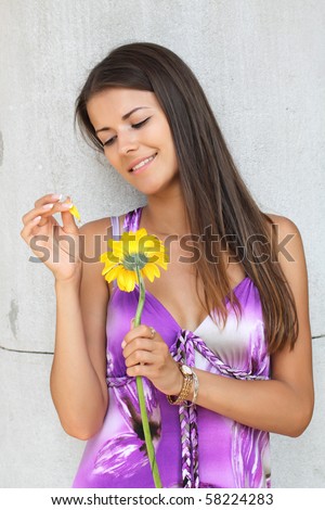 The girl in a lilac dress guesses on a flower Gerbera