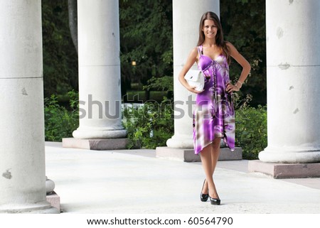 The girl in a lilac dress stand about a columns