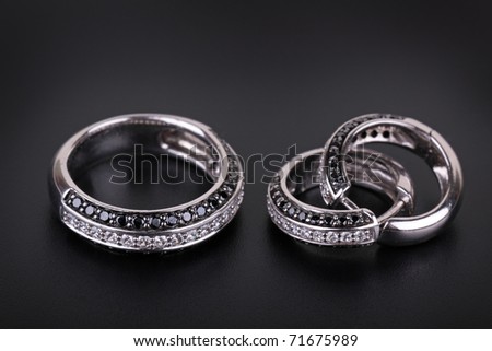 Ring from white gold and an earring with jewels on a black background