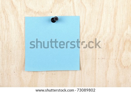 The blue note is pinned by the drawing-pin to a plywood board