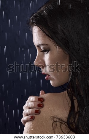 Portrait of the girl in a profile against a dark background with drops of water flowing from above