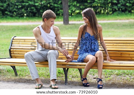 The guy and the girl on a bench in city park