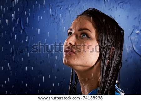 Portrait of the girl which looks upwards at flowing water against a dark blue wall