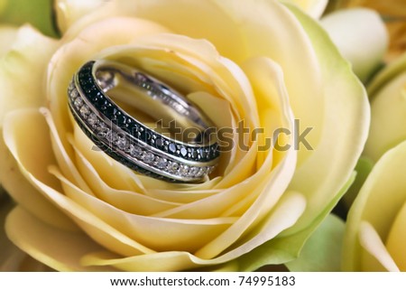 Ring from white gold with transparent and black brilliants in a bud of a yellow rose
