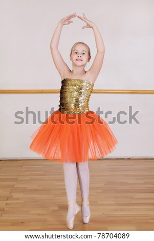 The young girl dances in a ballet orange tutu in the hall