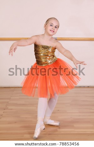The young girl dances in a ballet orange tutu in the hall