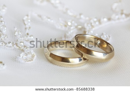stock photo Two wedding rings from yellow gold lie on a dress of the bride