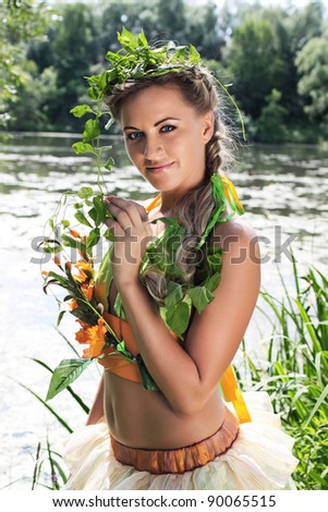 Portrait of a young girl on the bank of the river, dressed up for the holiday of Ivan Kupala (John Baptist's Day)