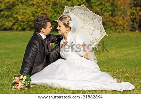 The couple sitting across from each other on the lawn in the park