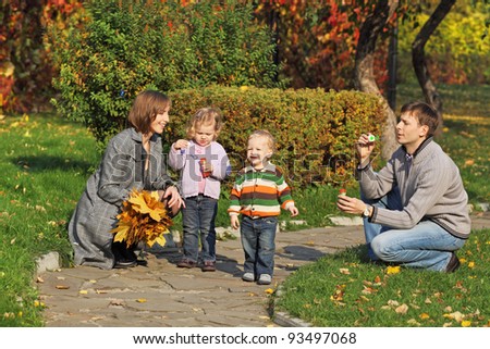 Young family for a walk in the autumn park with two children bubbles