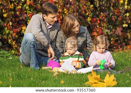 Mom, dad and two children for a walk in the park reading a book